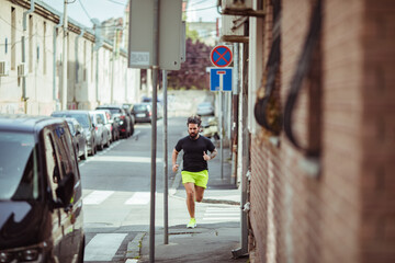 Man jogging in city street wearing neon shorts