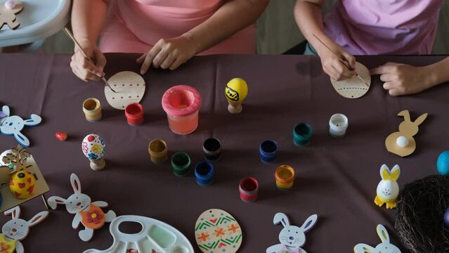 High angle view of family painting wooden eggs while sitting at table, preparing for Easter celebration