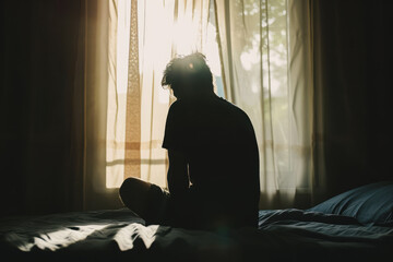 Silhouette of depressed man sitting on bed in front of window, Sleep problems due to stress, mental disorder