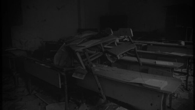 Old Deserted Abandoned School Vintage Film Texture Zoom Out. Abandoned school classroom with derelict chairs piled up, black and white. Old film texture, zoom out