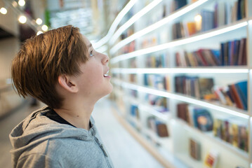 Young boy looking at bookshelf in library. 