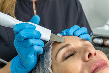 closeup of esthetician performing facial treatment on forehead woman
