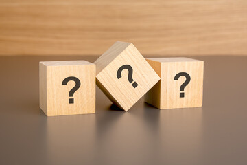 three wooden blocks on a brown background, with the question marks