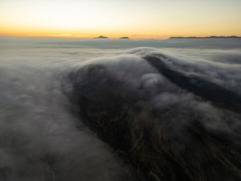 Dawn light suffuses the horizon as a blanket of clouds envelops the rugged terrain of Fuerteventura