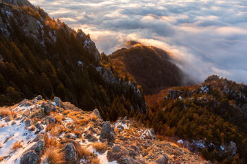 Snowy mountain slope above clouds at the sunrise