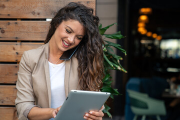 Smiling young beautiful business woman talking on a mobile phone while using fintech technology device.