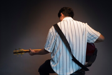 Musica. Güitarrista solitario, tocando una cancion en estudio. De espaldas. - obrazy, fototapety, plakaty