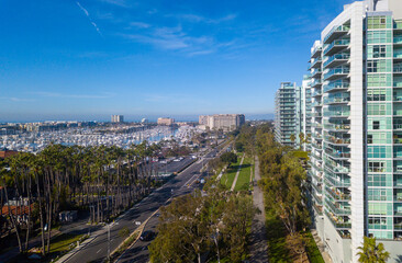 Fototapeta na wymiar Aerial views above Yvonne B. Burke Park and the Marvin Braude bike path in Marina Del Rey, California, overlooking the marina, high rise apartment buildings, and palm trees.