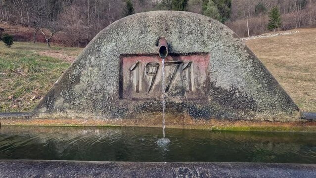 Ancient fountain from 1971 with rusty sections and very old located in the mountains of Carnia. Friuli Venezia Giulia, Italy. Naturalistic landscapes made of peace, tranquility and history.