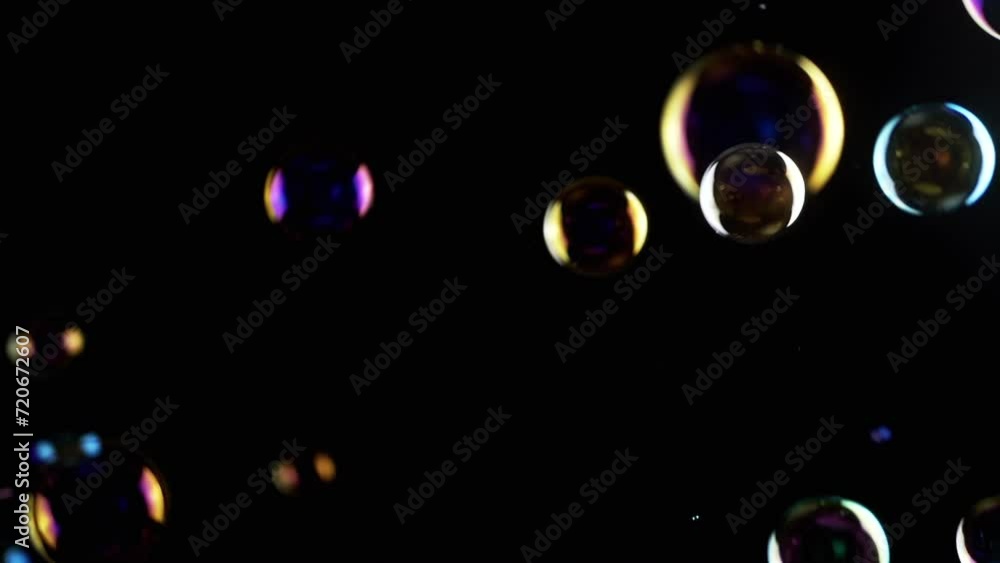 Poster colorful soap bubbles fly in empty space on isolated black background. colorful lights. many rainbow