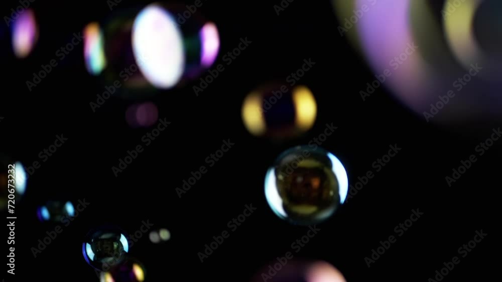 Poster colorful soap bubbles fly in empty space on isolated black background. colorful lights. many rainbow