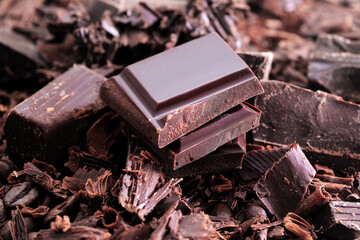 Broken dark chocolate bar and chocolate flakes on black kitchen table