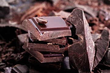 Broken dark chocolate bar and chocolate flakes on black kitchen table