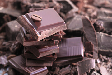 Broken dark chocolate bar and chocolate flakes on black kitchen table