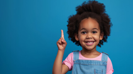 young African American girl with a big smile, wearing a pink shirt and a blue denim jumper, set against a light blue background