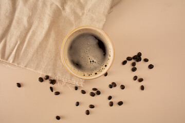 Coffee mug in a beige background with coffee beans and table cloth in aerial view