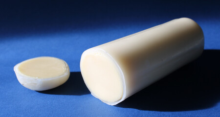String italian cheese in a paraffin coating isolated on blue background, close up.