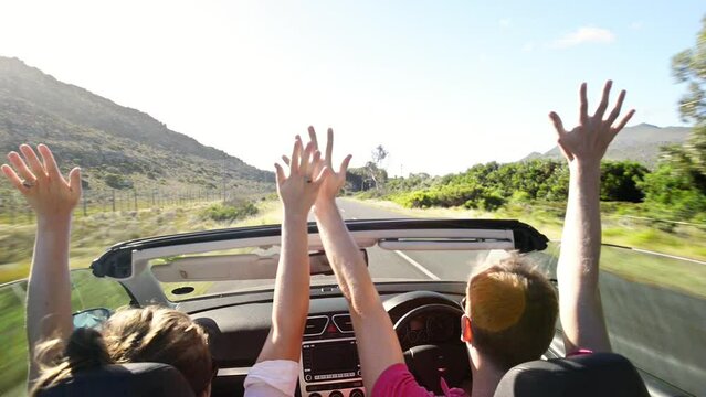 Couple, driving in car and celebration for road trip, outdoor adventure, and travel holiday by countryside. Back of people in fast convertible or transport with arms up, excited for vacation or speed