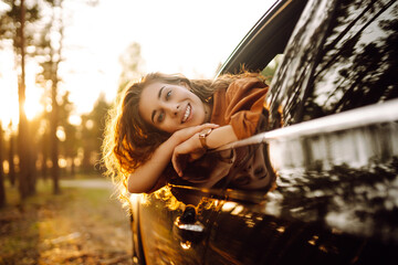 Young  woman leaning out of the car window enjoying nature. Lifestyle, travel, tourism, active life.