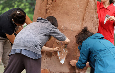 
Group of women working together on a large clay work. Ceramists making a sculpture in a community...