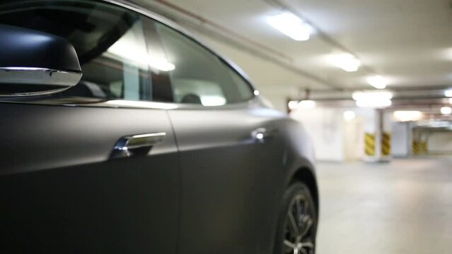 Woman in coat closes car door with shallow depth of field