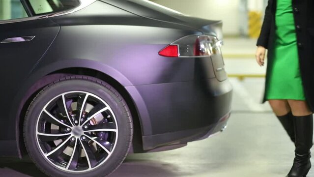 Woman closes trunk and goes away near Tesla S car
