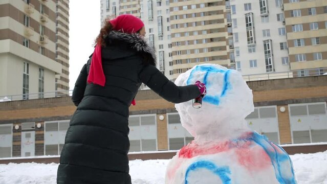 Woman painting square on snowman with aerosol spray can 