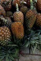 Ripe pineapples at the local farmer's market, lying in a pile on the floor - 720716816
