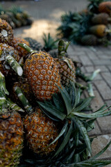 Ripe pineapples at the local farmer's market, lying in a pile on the floor - 720716831