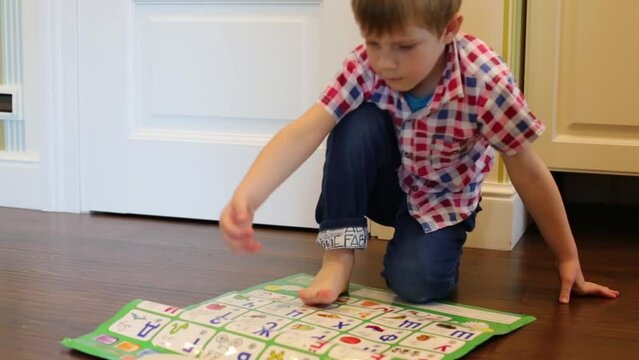 Little boy plays with interactive alphabet on floor in room