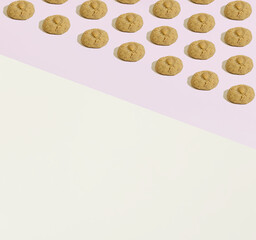 A pattern made of almond cookies geometrically laid out on a beige and pink background. Copy space. Sweets minimal concept.