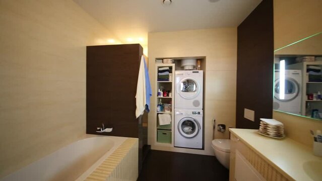 Interior of modern bathroom with toilet, bath and washing machine