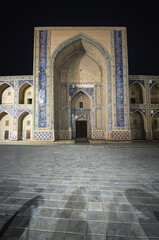 Fototapeta na wymiar Night exterior of an ancient madrasah mosque in the ancient city of Bukhara in Uzbekistan, the facade of the mosque is tiled with tiles, mosaics and majolica