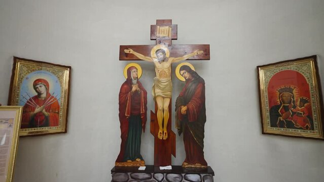 Crucifixion scene with Jesus on the cross, flanked by the Virgin Mary and Saint John, under an inscription, against a stone-like altar with a skull at the base, symbolizing Golgotha