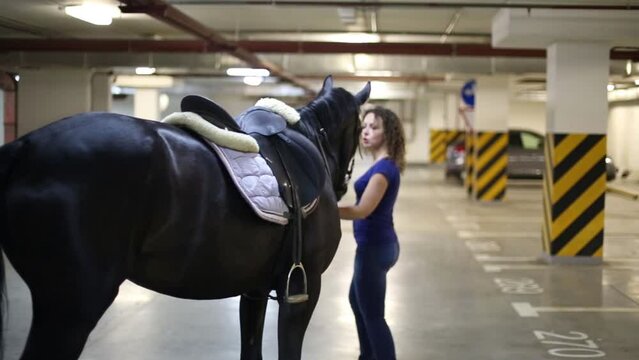 Woman walking with a horse on the underground parking