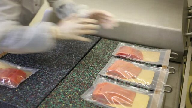 Employee arranges red fish in plastic bags on the machine for packaging