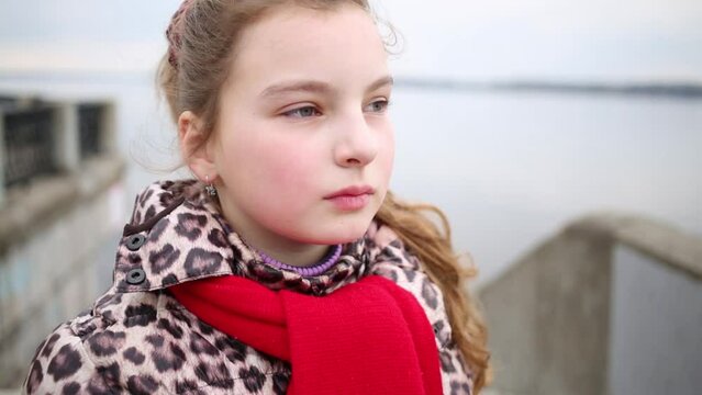 Face of young girl in spotted coat and red scarp close up.