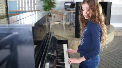 Girl in blue standing and playing piano and turning back.