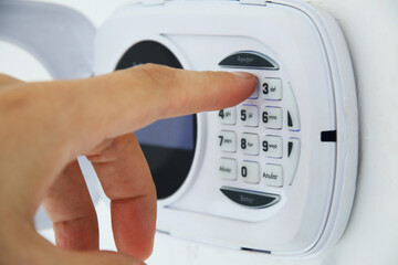 Person activating their home security alarm by typing the password on a keypad