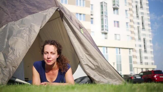 Woman in blue shirt lye and smile in tourist tent on lawn 