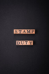 The inscription Stamp Duty made of wooden cubes on a plain background
