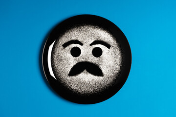 Smiling face, concept made with plate and flour, cyan background, star shaped eyes, black plate, happy mood, facial expressions
