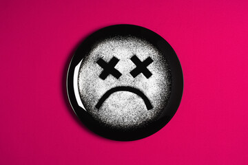 Sad face, concept made with plate and flour, red background, x-shaped eyes, black plate, happy mood, facial expressions