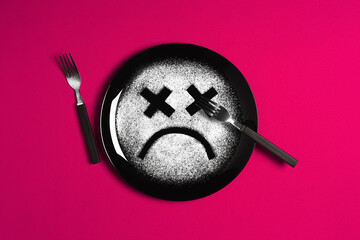 Sad face, concept made with plate and flour, majenta background, x-shaped eyes, black plate, happy mood, facial expressions, forks in the shape of arms with different positions