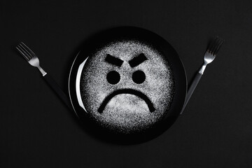 Displeased face, frowning eyebrows, concept made with plate and flour, black background, black plate, facial expressions, forks in the shape of arms with different positions