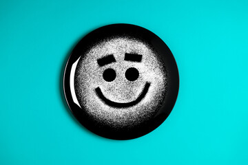 Smiling face, concept made with plate and flour, cyan background, star shaped eyes, black plate, happy mood, facial expressions