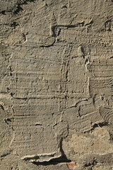 Old, sloppy, multi-layered wall covering of the house. Rough, uneven surface. Cement plaster on a brick wall, texture, background. Ancient backdrop of yellowed color. Contrasting view of wall cladding