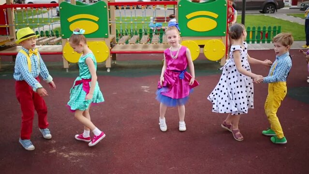 Five girls and boys and one girl energetic dancing twisting femor on playground