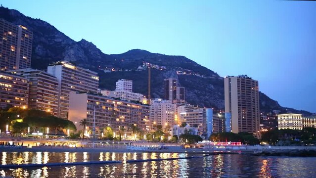 Evening cityscape with buildings on the seafront and mountains 