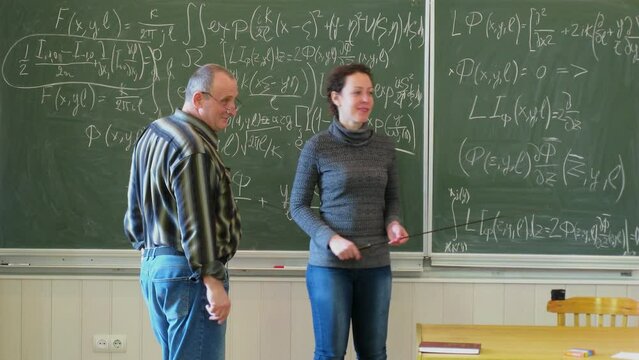 Teachers and children talk near chalkboard. Timelapse